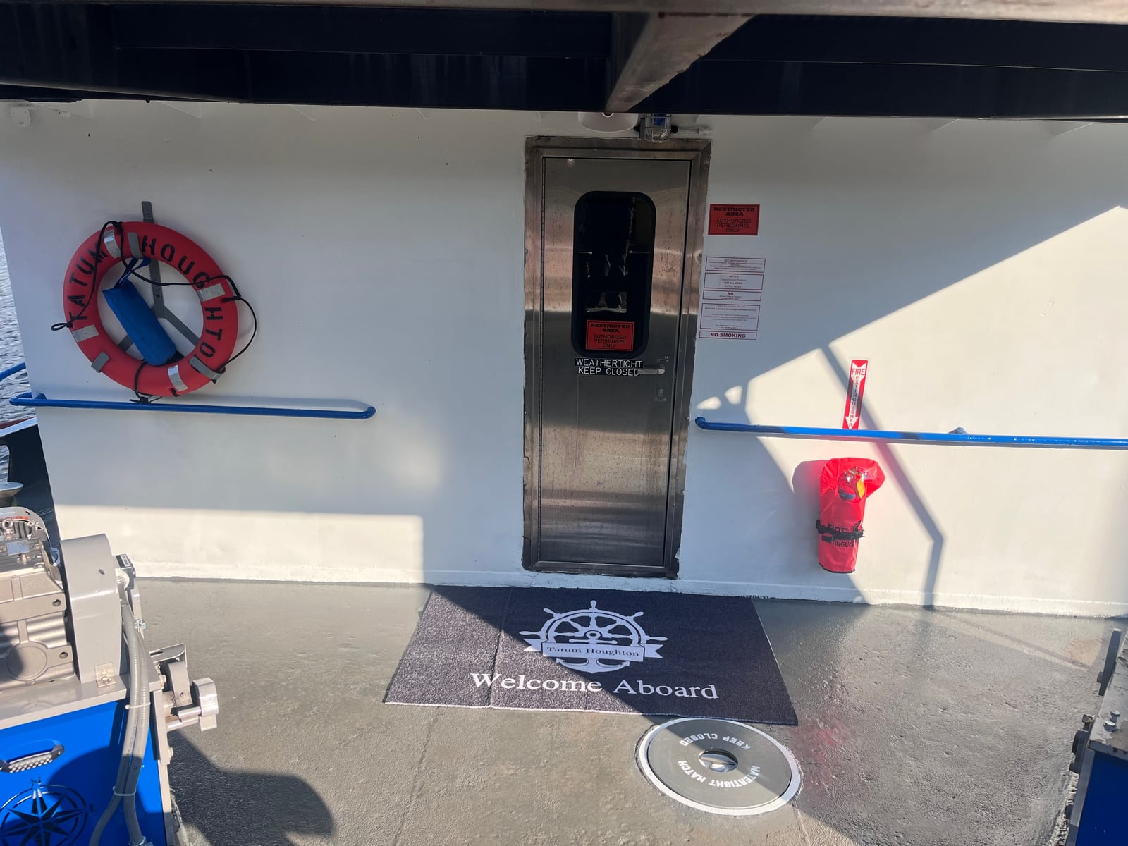 The cabin entrance on Tatum Houghton, with a life ring, fire extinguisher and welcome mat on the deck.